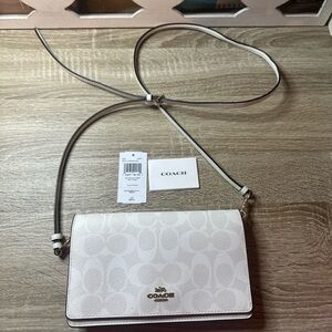Coach Anna Foldover Clutch Crossbody bag in a white signature canvas pattern.